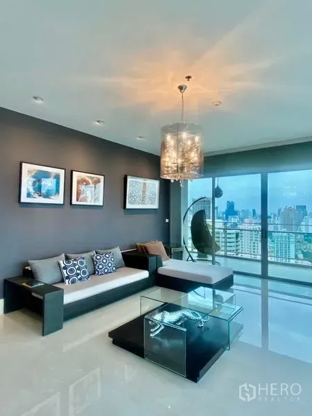 公寓 出租在Watthana, Bangkok - 现代客厅，水晶吊灯与玻璃茶几，落地窗连通观景阳台俯瞰城市。