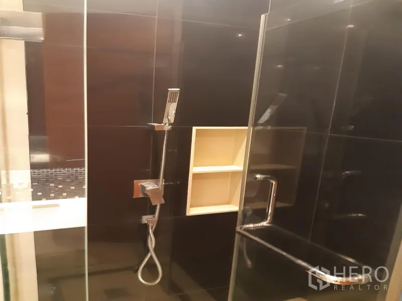 公寓 出租或出售在Khlong Toei, Bangkok - 步入式玻璃淋浴间，黑色瓷砖、手持花洒与内置壁龛。