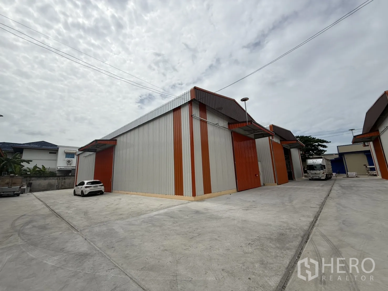 Warehouse for rent in Wang Thonglang, Bangkok - Row of warehouse units facing a wide concrete yard for car and truck access.