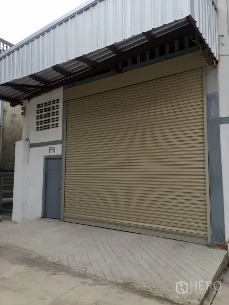 货栈 出租在Suan Luang, Bangkok - 曼谷Suan Luang仓库外观，配大尺寸卷帘门、金属雨棚与侧门。