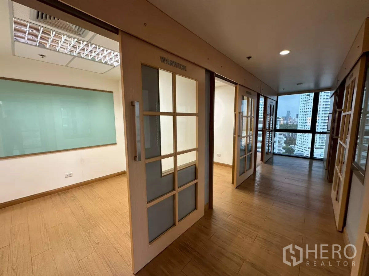 Office Space for rent in Khlong Toei, Bangkok - Row of private offices with glass boards and sliding doors near a corner window.