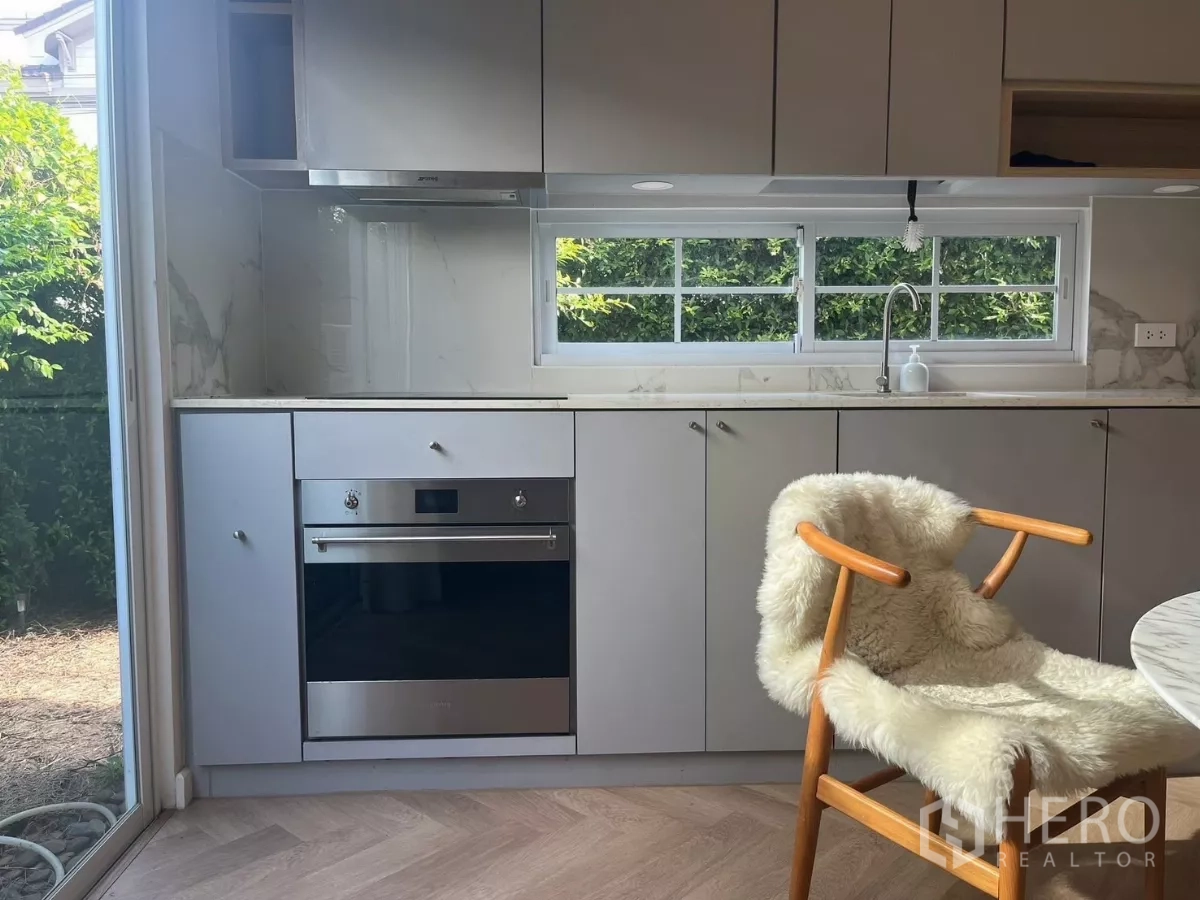 Townhouse for rent in Bang Phli, Samut Prakan - Built-in oven and induction hob beneath a window looking to the garden.