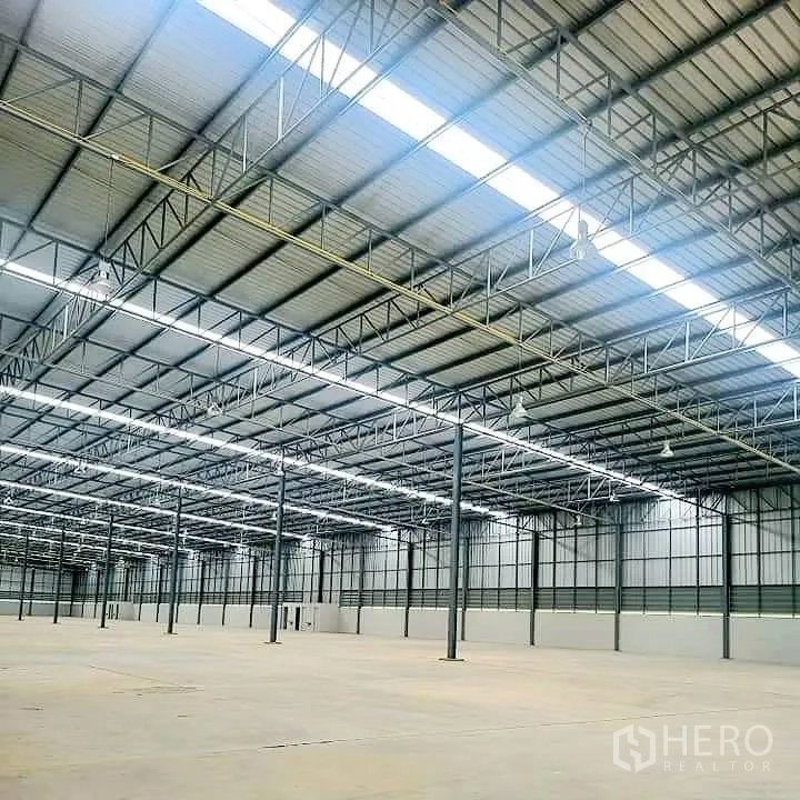 仓库 for rent in Lat Krabang, Bangkok - 屋顶钢桁架细节，连续天窗和照明设备的内部视角。