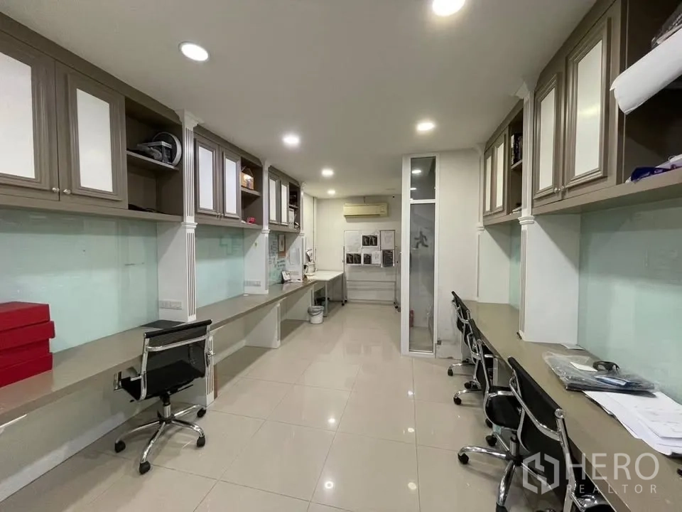 店屋 for sale in Prawet, Bangkok - 狭长工作区，成排内置柜与多张办公桌。