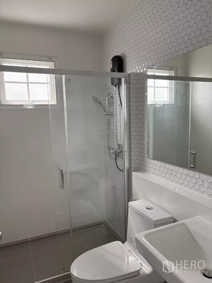 Detached House for rent or sale in Bang Phli, Samut Prakan - Modern bathroom with glass shower enclosure and hexagon tile wall.