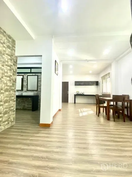 Townhouse for rent in Prawet, Bangkok - Hallway leading to dining and kitchen with stone accent wall and framed mirrors.