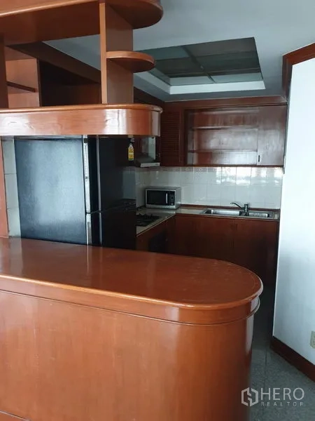 คอนโด ให้เช่าในWatthana, Bangkok - ครัวรูปตัวยูพร้อมตู้ไม้ ตู้เย็นสีดำ ไมโครเวฟ เตาแก๊ส และเคาน์เตอร์บาร์โค้ง