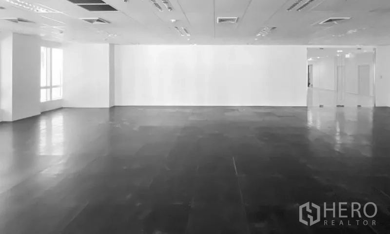 Office Space for rent - Empty white-walled office space with dark polished flooring, drop ceiling, and a glass entry doorway.