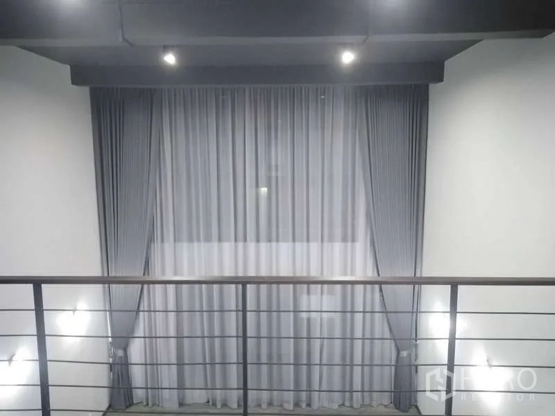 Home Office for rent or sale - Close view of mezzanine railing facing tall curtains and ceiling downlights.