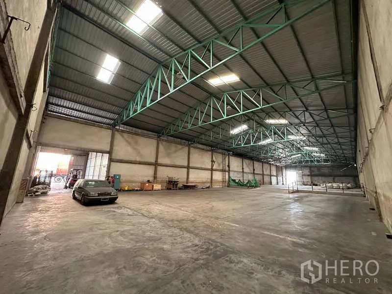 货栈 出租在Mueang Pathum Thani, Pathum Thani - 可驶入的仓库分区，装卸门旁停放车辆与设备。