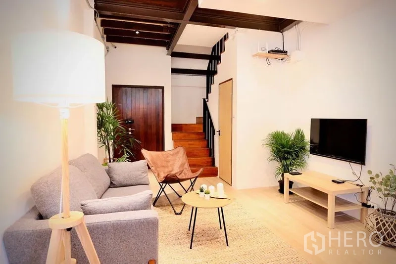 สำนักงาน ให้เช่าในSathon, Bangkok - ห้องนั่งเล่นสว่าง โซฟาสีเทา ทีวี บันไดไม้ ต้นไม้ในอาคาร และคานไม้เปลือย