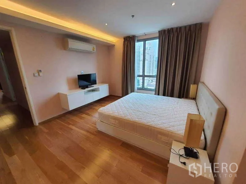 公寓 出售在Watthana, Bangkok - 宽敞主卧配电视、大窗与温润木地板。