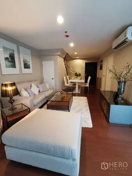 Condominium for rent or sale in Huai Khwang, Bangkok - Alternate angle of the living room showing sofa, ottoman and connected dining area.
