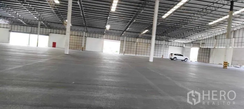 Warehouse for rent in Bang Pakong, Chachoengsao - Expansive open-plan warehouse interior with high steel roof, bright strip lighting and smooth concrete floor.