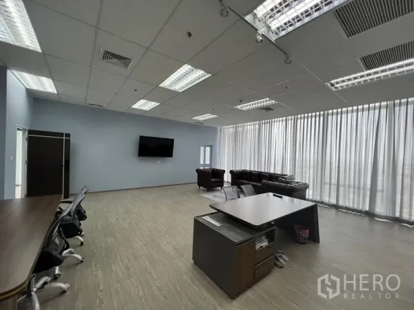 办公空间 出租 - 宽敞的开放式办公室，落地窗纱帘、办公桌与休息区，网格吊顶灯。