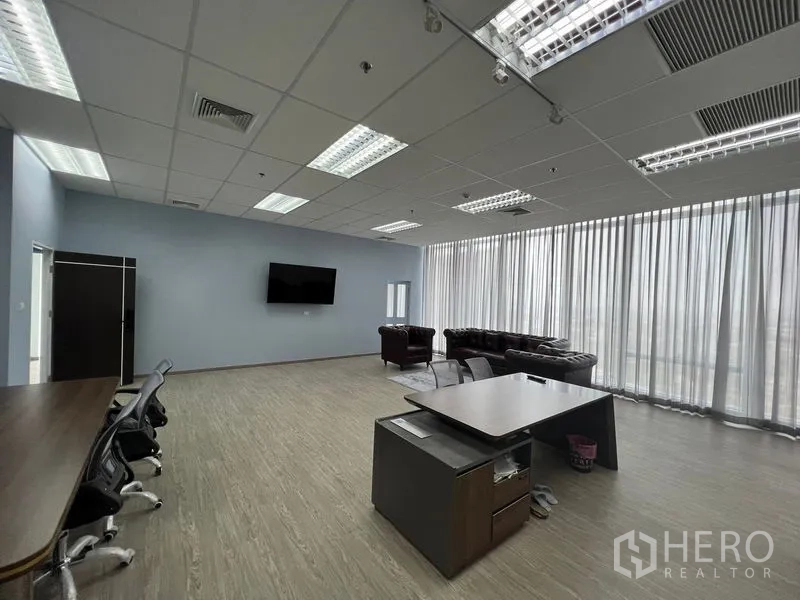 办公空间 出租 - 宽敞的开放式办公室，落地窗纱帘、办公桌与休息区，网格吊顶灯。