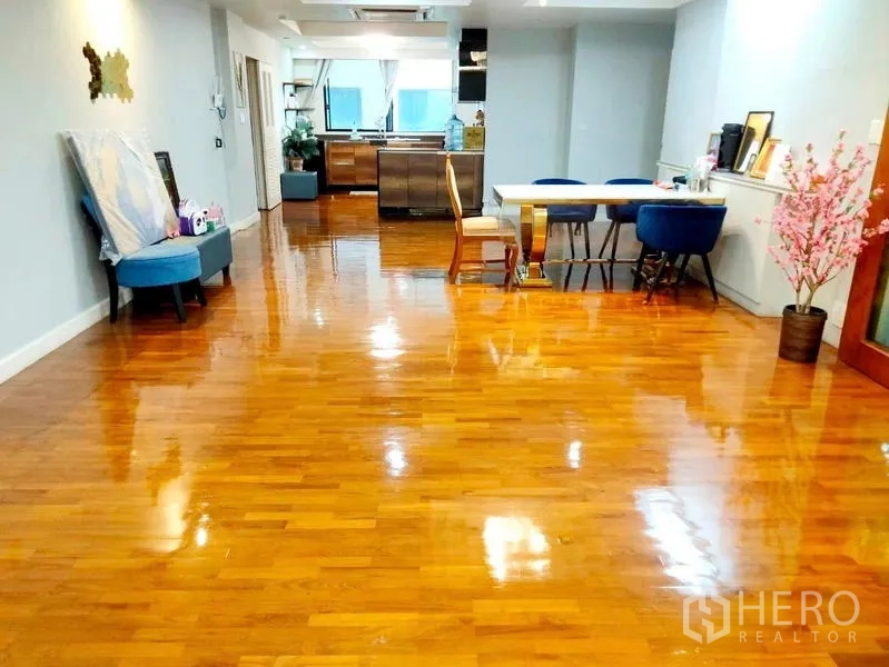 Condominium for rent in Khlong Toei, Bangkok - Spacious open-plan living and dining with glossy hardwood floors and ceiling lights at President Park condo.