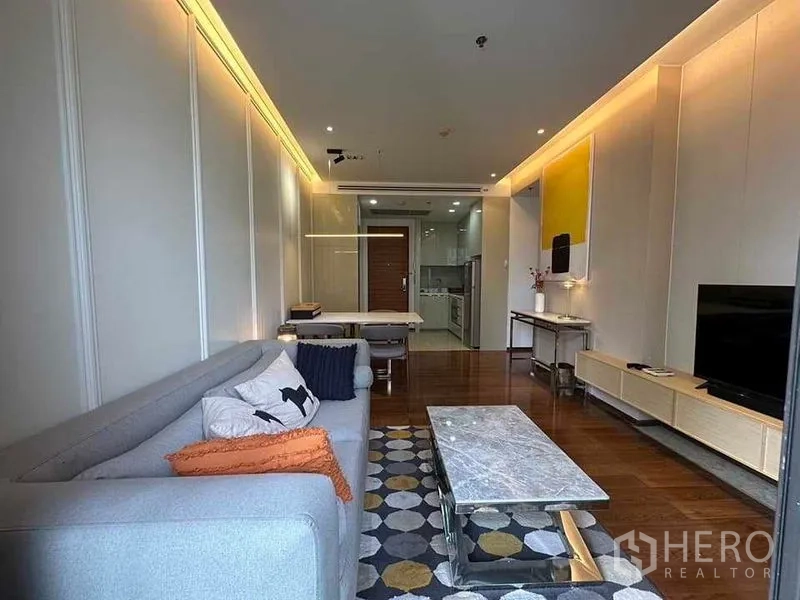 คอนโด ให้เช่าในKhlong Toei, Bangkok - ห้องนั่งเล่นมองไปยังครัว โต๊ะกลางหินอ่อน ชั้นวางทีวี และประตูออกไประเบียง