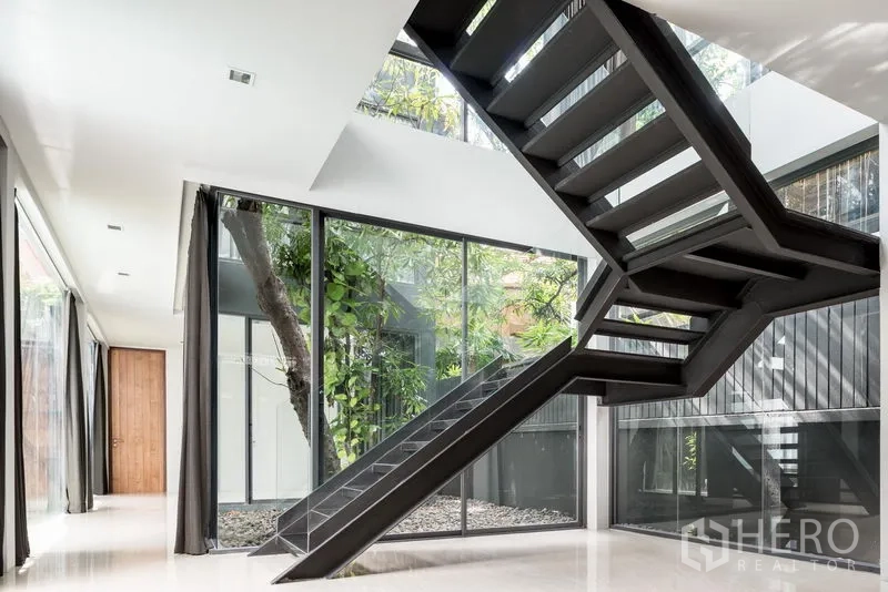 Home Office for rent in Khlong Toei, Bangkok - Double-height atrium featuring a black steel staircase and floor-to-ceiling glass facing an inner garden.