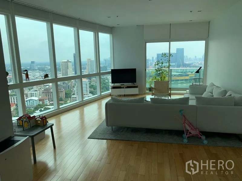 คอนโด ให้เช่าในKhlong Toei, Bangkok - ห้องนั่งเล่นมุมกระจกเต็มผนัง พื้นไม้ สีสว่าง พร้อมวิวสกายไลน์กรุงเทพฯ