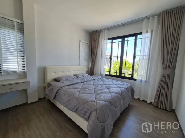 Detached House for rent in Samut Prakan - Bright bedroom with a large window, sheer curtains and garden outlook.