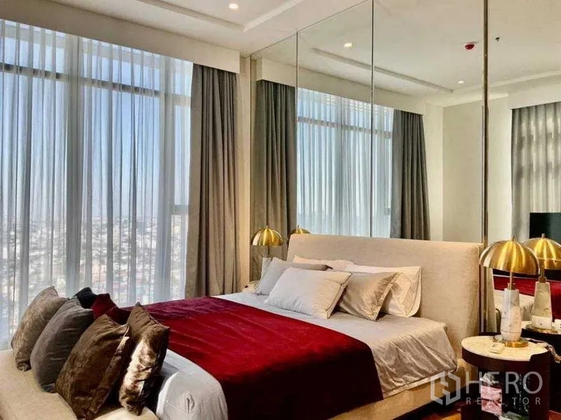 公寓 出售 - 采光充足的主卧，纱帘后城市景观与金色床头灯。