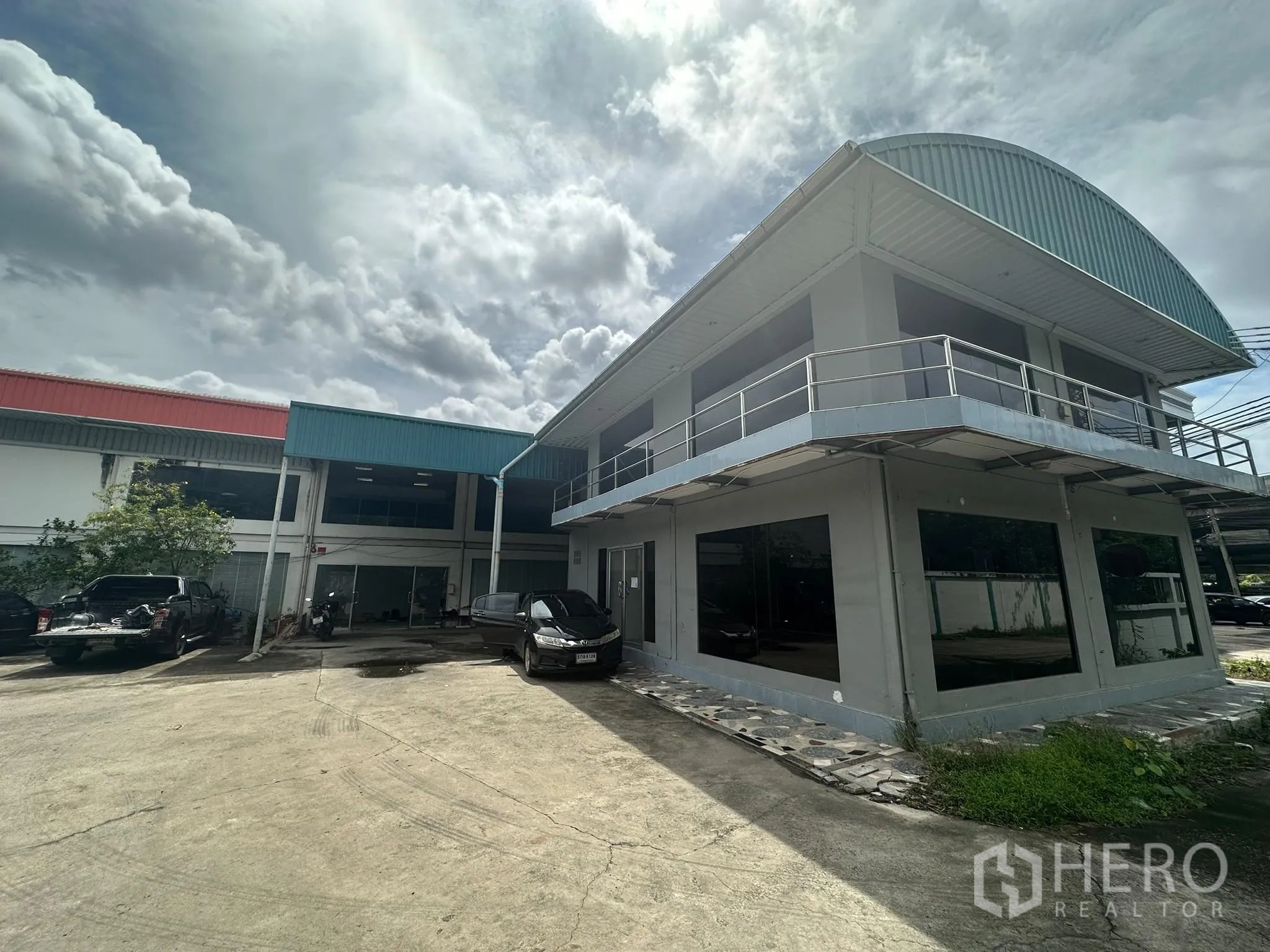 Warehouse for rent in Huai Khwang, Bangkok - Two-storey office block with balcony beside a warehouse and wide concrete yard.