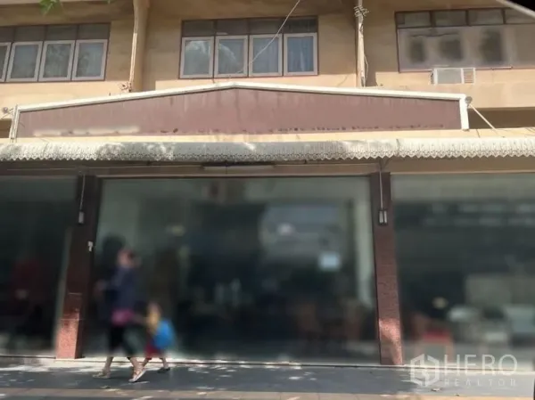 零售空间 出租在Watthana, Bangkok - 中央店面，宽大招牌位与展示玻璃，前方为阴凉人行道。