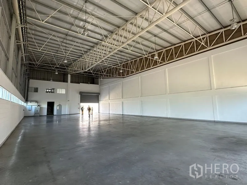 Factory for rent in Bang Bo, Samut Prakan - Warehouse bay with roller shutter door, concrete floor and mezzanine office area.