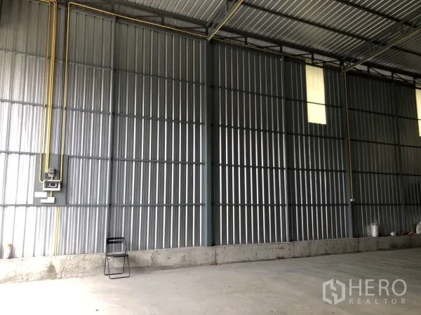 Warehouse for rent in Wang Thonglang, Bangkok - Interior metal wall panels with electrical conduits and high windows for light.