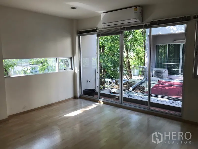 ทาวน์เฮาส์ ให้เช่าในSuan Luang, Bangkok - ห้องนอนพื้นไม้สีอ่อน ประตูกระจกกว้างออกสู่ระเบียงที่มีต้นไม้