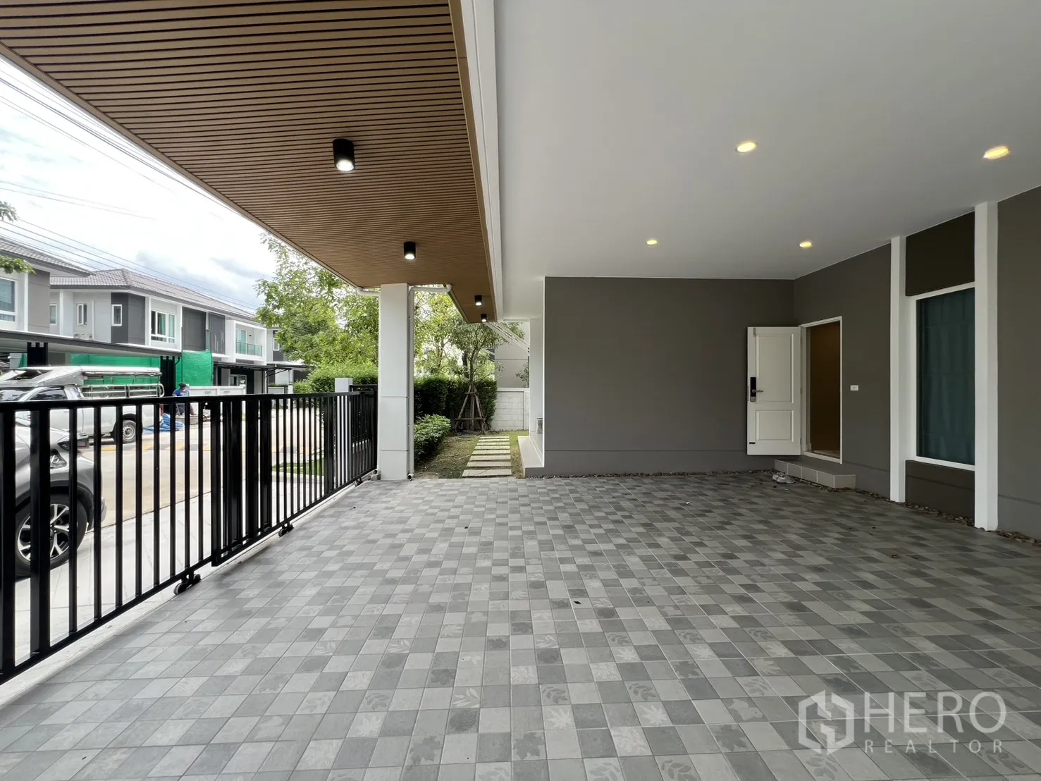 Detached House for rent in Lat Krabang, Bangkok - View of the carport toward the street with a black metal sliding gate and ceiling downlights.