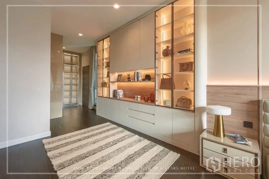 Detached House for rent or sale in Suan Luang, Bangkok - Bedroom corridor with built-in illuminated display cabinets and a striped rug.