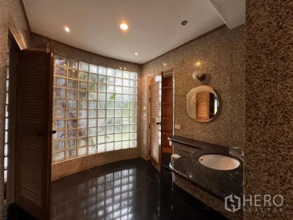 ทาวน์เฮาส์ ให้เช่าในKhlong Toei, Bangkok - ห้องน้ำกว้างพร้อมหน้าต่างบล็อกแก้วโค้ง ผนังแกรนิต และเคาน์เตอร์อ่างล้างหน้า