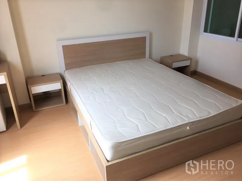 Condominium for rent in Watthana, Bangkok - Spacious bedroom featuring a queen bed frame with side tables and laminate flooring.