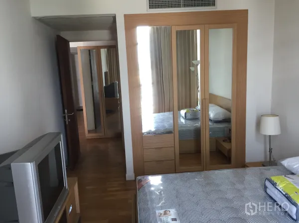 Condominium for rent in Sathon, Bangkok - Cozy bedroom with mirrored sliding-door wardrobe, wooden furnishings, double bed, and hardwood floors.