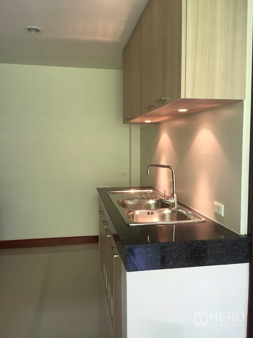 Detached House for rent in Sathon, Bangkok - Kitchen sink area with double stainless sinks, under-cabinet lighting and black stone counter.