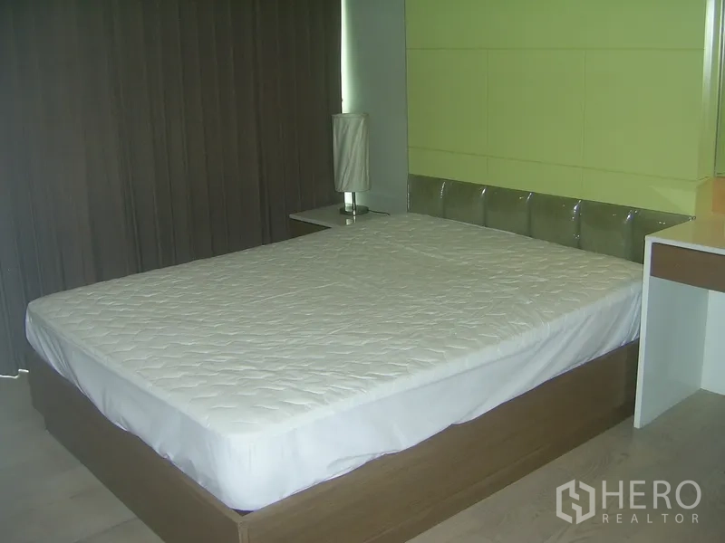 คอนโด ให้เช่าในKhlong Toei, Bangkok - ห้องนอนที่สองผนังสีเขียว เตียงขนาดใหญ่และโคมโต๊ะข้างเตียง