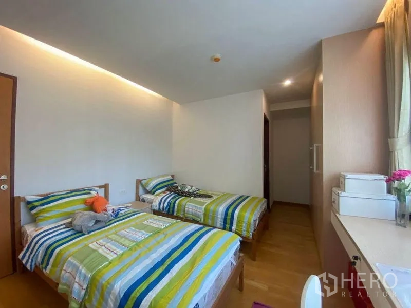 คอนโด ให้เช่าหรือขายในPhra Khanong, Bangkok - ห้องนอนเตียงคู่ ผ้าปูสีสันสด ตู้บิวท์อิน หน้าต่างและโต๊ะทำงานยาว