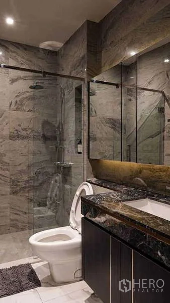 Condominium for rent or sale in Watthana, Bangkok - Luxurious bathroom with marble walls, glass shower, vanity and toilet.