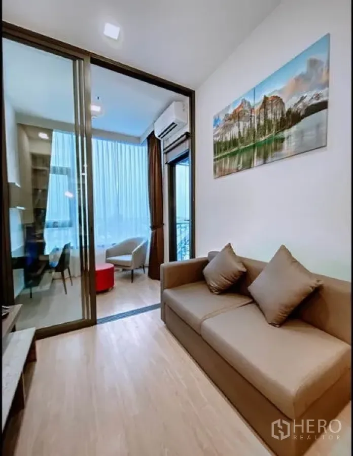 Condominium for sale in Chatuchak, Bangkok - Bright living room with sofa, sliding glass door and balcony access in a Chatuchak condo.