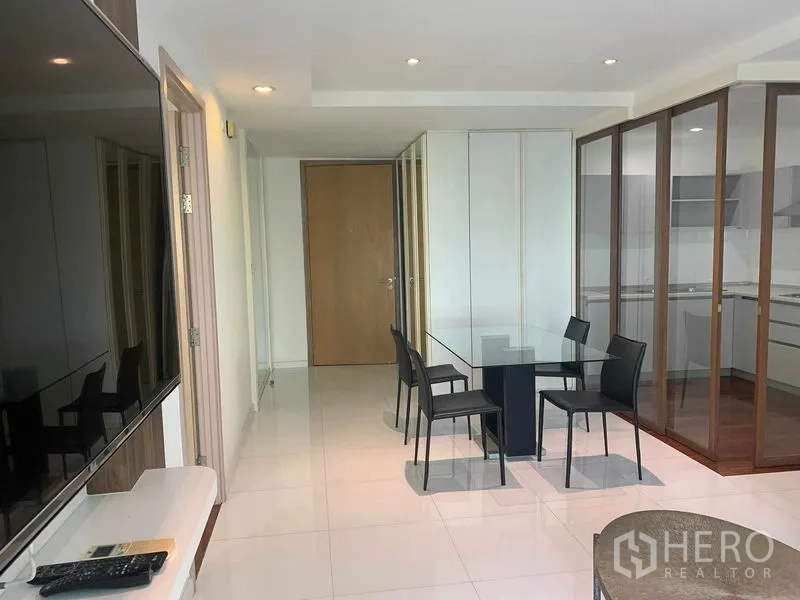 公寓 出租或出售在Khlong Toei, Bangkok - 餐区四把椅，厨房在玻璃隔断后。