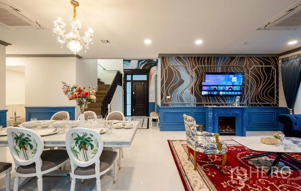 Detached House for rent or sale in Khlong Toei, Bangkok - Open-plan living and dining area with chandelier, TV feature wall and classic blue paneling.
