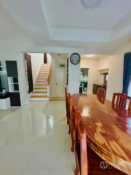 Detached House for sale in Prawet, Bangkok - Open dining area with glossy tile flooring, wooden table set and stairs to the upper floor.