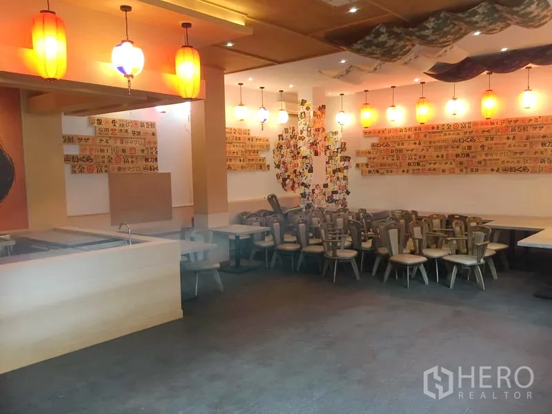 零售空间 出租在Khlong Toei, Bangkok - 宽敞用餐区，吊灯照明，墙面菜单板，堆放的椅子待布局。