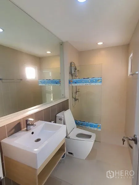 Townhouse for rent in Wang Thonglang, Bangkok - Modern bathroom with large mirror, glass shower and white vanity.