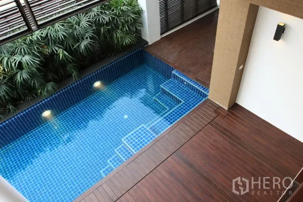 Detached House for rent in Khlong Toei, Bangkok - Private blue-tiled plunge pool with underwater lights beside a wooden deck and tropical plants.