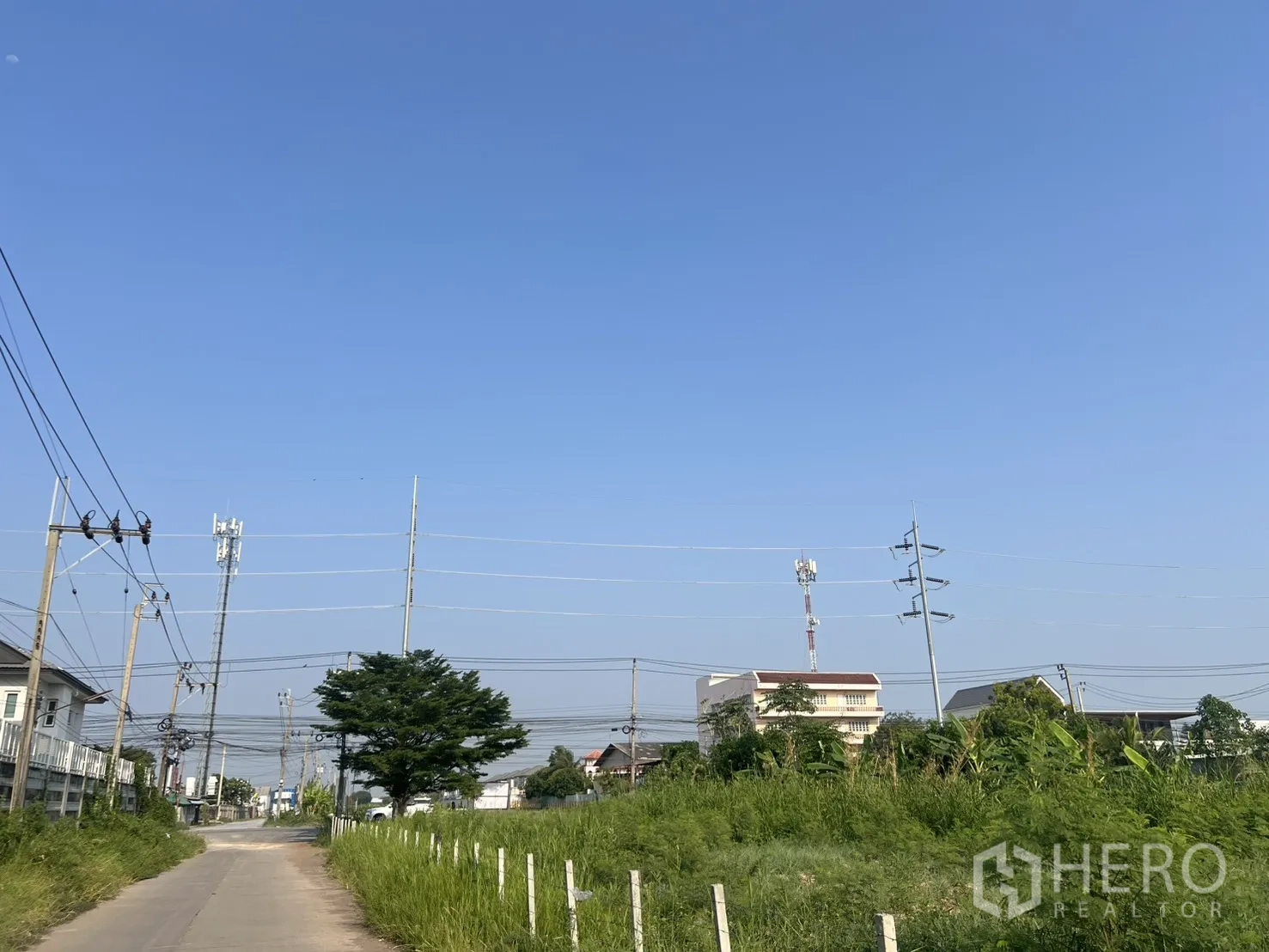 Land for sale in Lat Krabang, Bangkok - Approach road with power lines and nearby buildings next to the land.