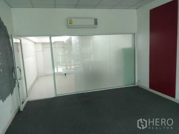 零售空间 出租在Huai Khwang, Bangkok - 铺地毯的房间，磨砂玻璃隔断，挂墙空调与玻璃门。
