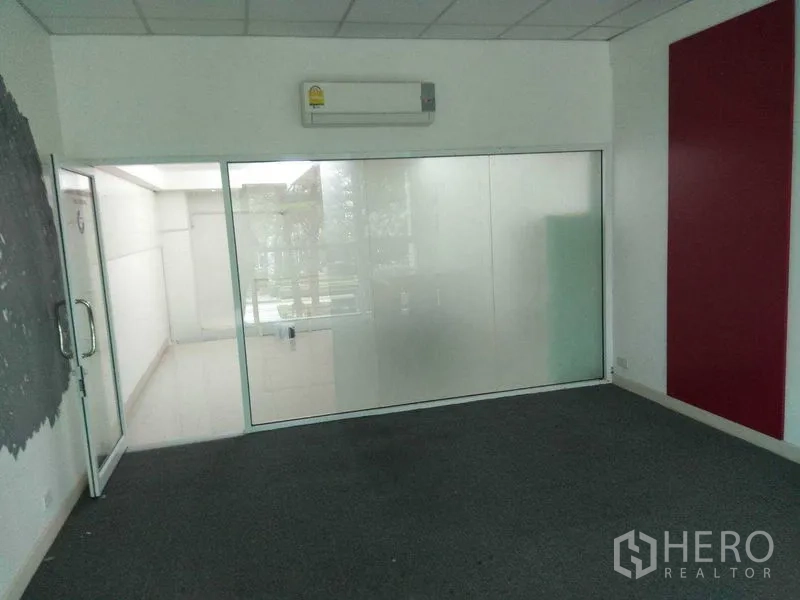 零售空间 出租在Huai Khwang, Bangkok - 铺地毯的房间，磨砂玻璃隔断，挂墙空调与玻璃门。